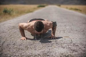 maschio atleta esercizio spingere su al di fuori nel soleggiato luce del sole. in forma A petto nudo maschio fitness modello nel CrossFit esercizio all'aperto. salutare stile di vita concetto. foto