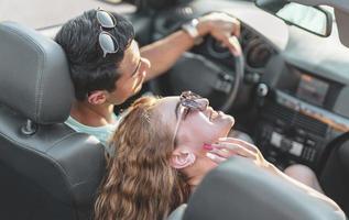 amici avendo divertimento a auto viaggio in giro il mondo. coppia nel amore con braccia su su un' convertibile macchina. foto