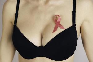 Salute cura, medicina e Seno cancro consapevolezza concetto. giovane donna nel reggiseno con rosa nastro simbolo foto