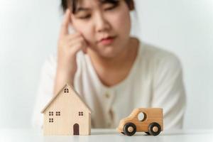 confuso asiatico donna acquirente la scelta fra acquisto nuovo casa o macchina. foto