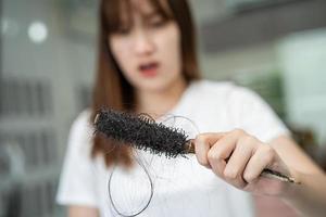 la donna asiatica ha problemi con la caduta dei capelli lunghi attaccata alla spazzola del pettine. foto