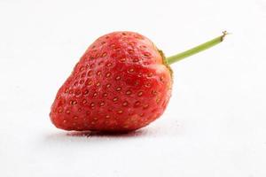 avvicinamento un' fresco fragola su un' bianca dipinto di legno base insieme a. macro fotografia foto