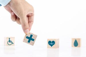 l'uomo d'affari sceglie un simbolo medico sanitario delle icone di emoticon sul blocco di legno, sul concetto di assicurazione sanitaria e medica foto
