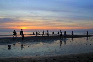viaggio per isola KOH cambiare, Tailandia. il giovane ragazzi siamo giocando calcio su il spiaggia su il sfondo di colorato tramonto. foto