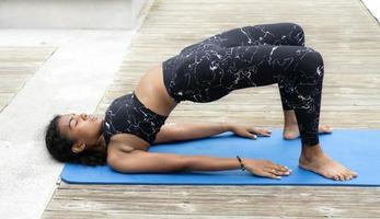 africano americano donna esercizio yoga all'aperto nel il parco. giovane multirazziale persona godere tempo libero attività allungamento esercizio e Meditare per corpo parte flessibilità. vero persone salutare stile di vita foto