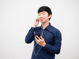 asiatico uomo ascoltando musica con auricolare e hold cellulare contento e rilassare emozione foto