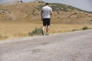 giovane uomo corridore in esecuzione su un' montagna strada. jogger formazione allenarsi nel fitness scarpa. salutare stile di vita e sport concetto. movimento sfocatura e selettivo messa a fuoco. foto