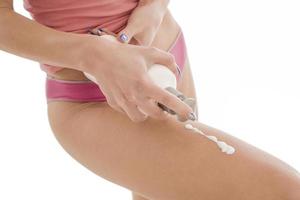 corpo cura. donna l'applicazione crema su gambe. femmina l'applicazione anti cellulite crema foto