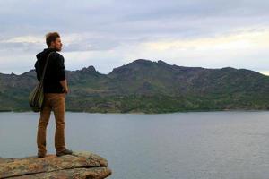 viaggio per kazakistan, bayanaul nazionale parco. il giovane uomo è guardare in il distanza un' lago e montagne. foto