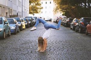 giovane donna fare handstand su città strada foto