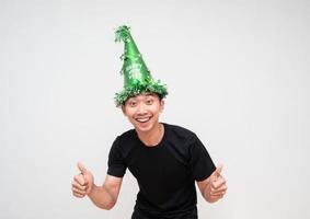 giovane asiatico uomo con verde cappello contento Sorridi allegro Doppio pollice su su bianca isolato sfondo celebrazione contento nuovo anno concetto foto