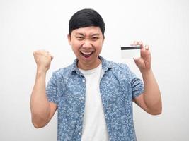 asiatico uomo contento con credito carta nel mano e cazzotto su successo foto