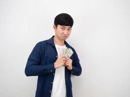 giovane asiatico uomo Tenere i soldi lesinare Guarda a viso su bianca sfondo foto