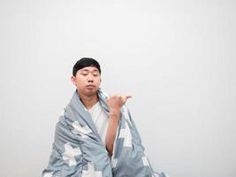 asiatico uomo copertina corpo di coperta e annoiato viso punto dito giusto lato copia spazio su bianca sfondo, no volere per scia su concetto foto