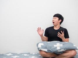 asiatico uomo Tenere mobile Telefono su il letto sensazione stupito guardare a copia spazio foto