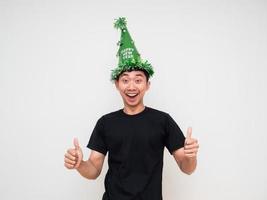 giovane asiatico uomo con verde cappello contento Sorridi allegro Doppio pollice su su bianca isolato sfondo celebrazione contento nuovo anno concetto foto