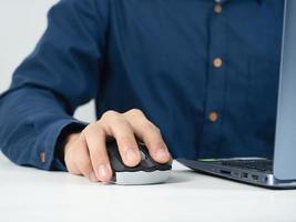 avvicinamento uomo mano catturare topo il computer portatile Lavorando su il tavolo foto