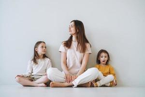 giovane contento madre con Due bambini ragazze su il sfondo di grigio parete foto