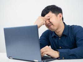 uomo con il computer portatile provato a partire dal Lavorando e sentire affaticamento degli occhi, schiacciamento occhio foto