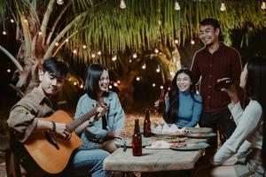 asiatico gruppo persone giocando chitarra a il festa e birra potabile foto