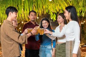 gruppo di amici felicemente in piedi e tostatura birre a il festa. foto