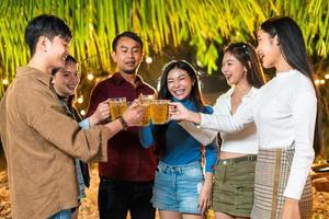 gruppo di amici in piedi e tostatura birre a un' festa foto