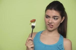 ritratto di un' contento giocoso ragazza mangiare fresco insalata a partire dal un' arco foto