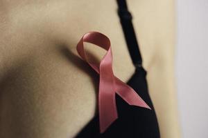 Salute cura, medicina e Seno cancro consapevolezza concetto. giovane donna nel reggiseno con rosa nastro simbolo foto