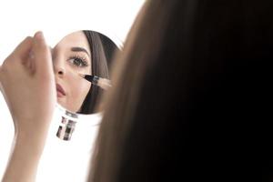 ritratto di un' giovane donna l'applicazione liquido rendere su su sua viso. isolato su bianca sfondo foto
