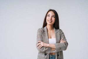 giovane contento asiatico donna con lungo capelli nel completo da uomo su grigio sfondo foto