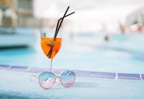 bicchiere di cocktail con ghiaccio e occhiali da sole su Hotel piscina, estate vacanza foto