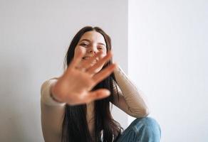 giovane sorridente donna adolescente ragazza con buio lungo capelli nel jeans nel sua camera a il casa foto