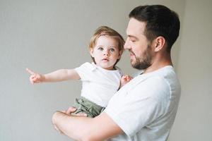 contento padre giovane uomo e bambino ragazza poco figlia avendo divertimento nel bambini camera a casa foto