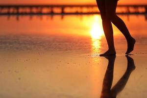 metraggio vista laterale di bella giovane donna in costume da bagno che cammina sulla spiaggia verso il mare. la ragazza è molto magra foto