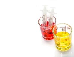 rosso e giallo liquido medicina nel medicina misurazione bicchiere tazza con plastica siringhe per pronto per accedere il paziente bocca isolato su bianca sfondo e rendere con percorsi. foto