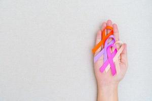 mondo cancro giorno, febbraio 4. mano Tenere arancia, rosa, pesca e viola nastri per supporto persone vivente e malattia. assistenza sanitaria e medico concetto foto