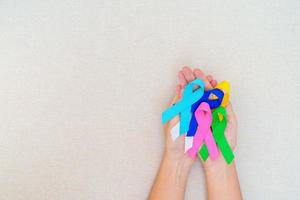 mondo cancro giorno, febbraio 4. mano Tenere blu, rosso, verde, bianca, rosa, Marina Militare blu e giallo nastri per supporto persone vivente e malattia. assistenza sanitaria e autismo consapevolezza giorno concetto foto