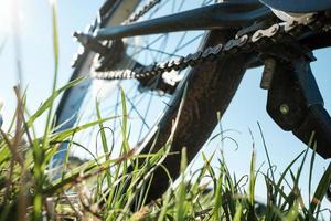 avvicinamento dettaglio di un' bicicletta parcheggiata nel un' prato, contro il fondale di il sole e blu cielo. attivo stile di vita concetto. parte inferiore Visualizza. foto