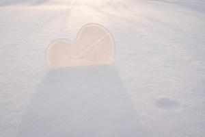 cuore è un' simbolo di amore, fatto di Ghiaccio, nel il neve, nel il raggi di il sole. San Valentino giorno. romantico concetto. copia spazio. foto