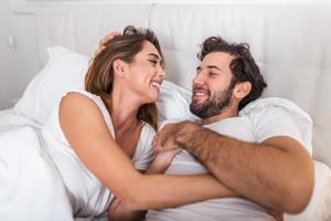 bellissimo amorevole coppia baci nel letto. bellissimo giovane coppia dire bugie insieme su il letto. romantico giovane coppia nel amore dire bugie su letto. bellissimo coppia sorridente nel letto. foto