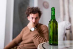 depresso triste giovane dipendente uomo sensazione cattivo potabile birra solo a casa, stressato frustrato solitario bevitore alcolizzato soffrire a partire dal alcool dipendenza avendo problema, alcolismo concetto foto