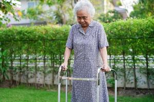 camminata del paziente di disabilità della donna anziana asiatica con il deambulatore nell'ospedale di cura, concetto medico. foto