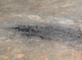 nero fuliggine o olio chiazza di petrolio a partire dal auto scarico tubo caduta su sporco cemento o calcestruzzo pavimento nel vecchio box auto foto