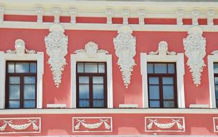 finestre bellissimo ornato restaurato rosa Casa con bianca stucco decorazioni. edificio facciata elemento. foto