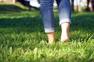 asiatico donna a piedi a piedi nudi su il erba per sentire il natura contribuisce per fabbricazione persone sentire a pace avere Di Più mentale stabilità. morbido e selettivo messa a fuoco. foto