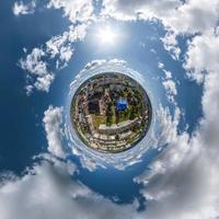 minuscolo pianeta nel cielo con nuvole prospiciente vecchio cittadina, urbano sviluppo, storico edifici e incrocio stradale. trasformazione di sferico 360 panorama nel astratto aereo Visualizza. foto