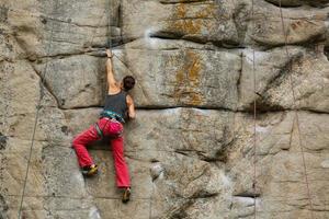 un' giovane donna con un' corda impegnato nel il gli sport di roccia arrampicata su il roccia. foto