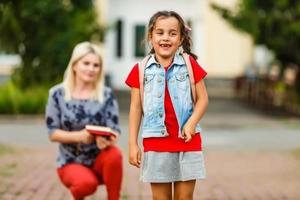 giovane madre conduce sua figlia per scuola. foto