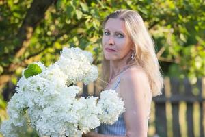 bellissimo anziano donna con un' mazzo di fiori. sorridente donna nel sua giardino. foto