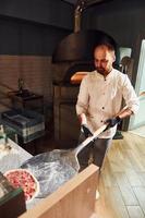 capocuoco nel bianca Abiti preparazione delizioso Pizza su il cucina di ristorante foto